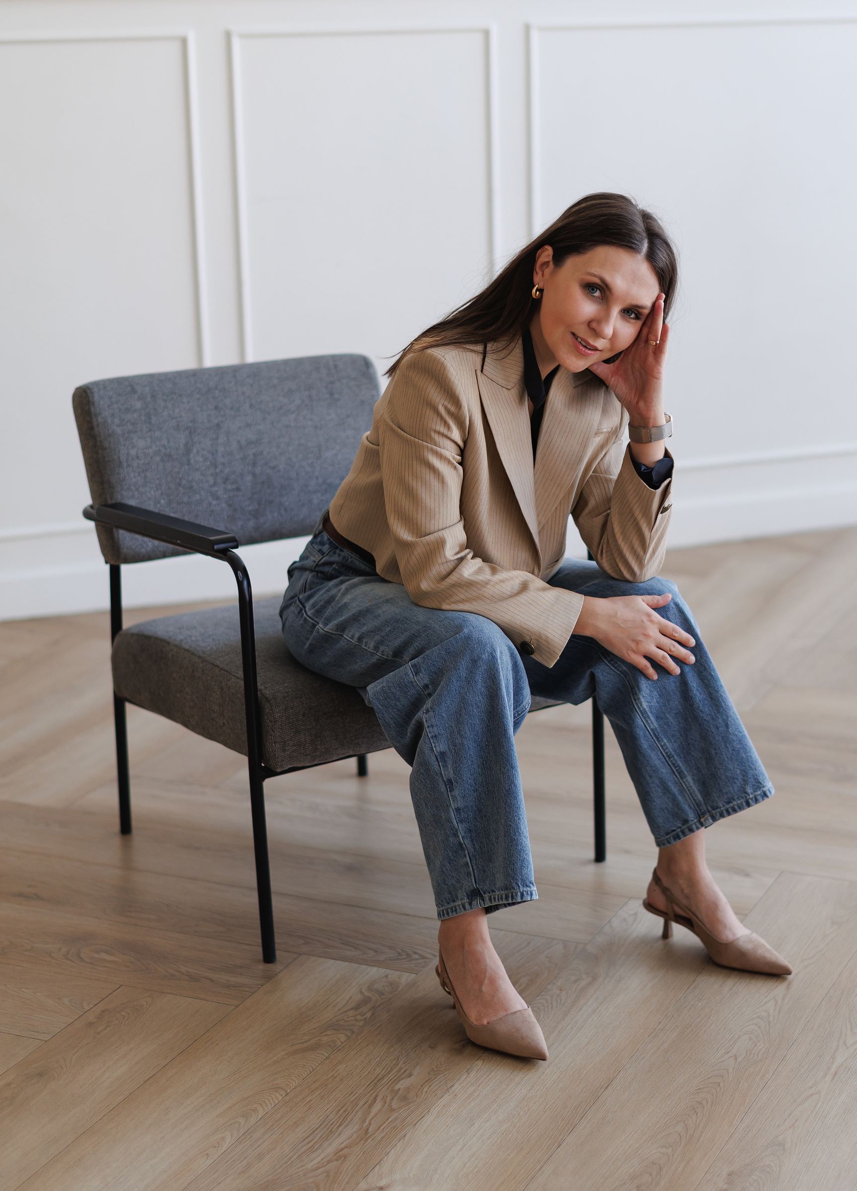 Karina Wolf seated in an armchair in a panelled room with a herringbone floor