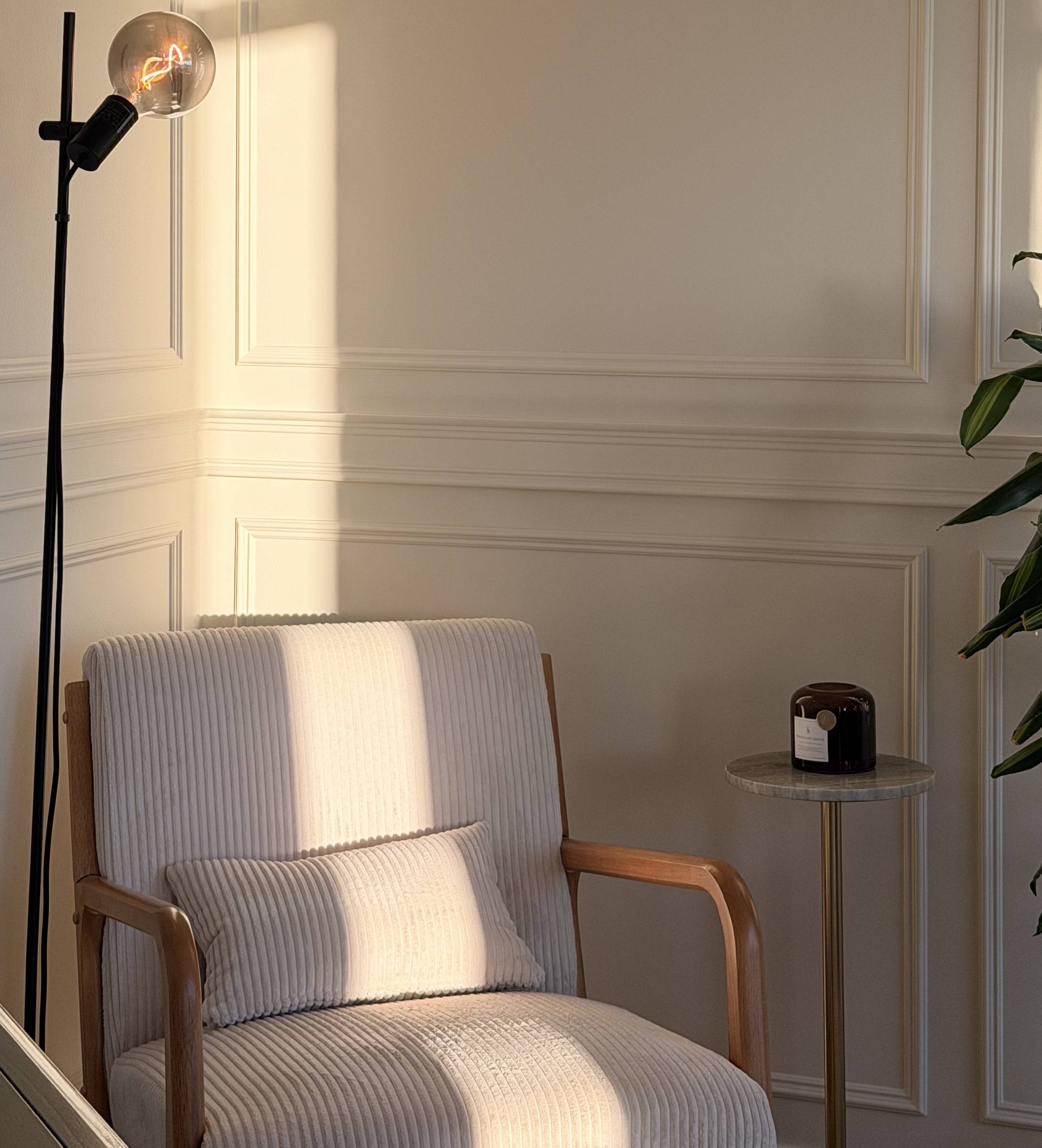 Panel moulding wall in warm evening light with an armchair and floor lamp